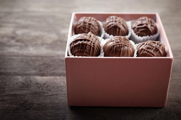 Lekkere chocolade snoepjes in roze geschenkdoos op houten ondergrond, close-up