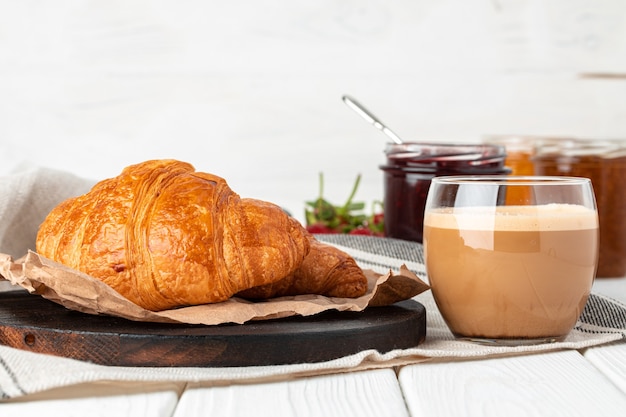 Lekkere croissant met kopje koffie met melk op keukentafel