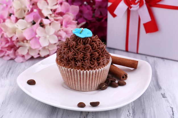 Lekkere cupcake met botercrème op plaat op een houten achtergrond kleur