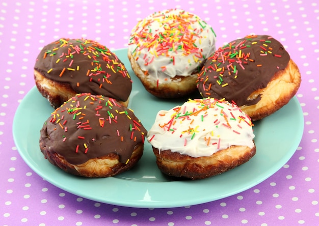 Lekkere donuts op kleurenplaat op gekleurde achtergrond