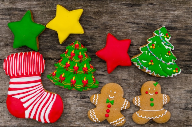 Lekkere feestelijke kerstkoekjes in de vorm van een kerstboom, Gingerbread man, ster en kerstsok op rustieke houten tafel. Bovenaanzicht