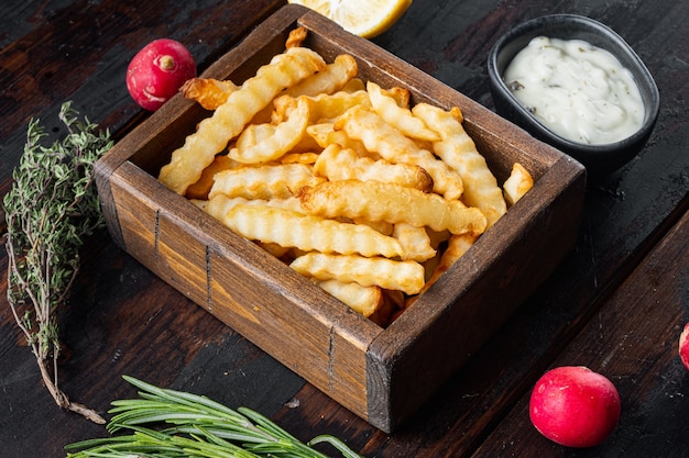 Lekkere frietjes met kruiden in houten doos op oude donkere houten tafel achtergrond