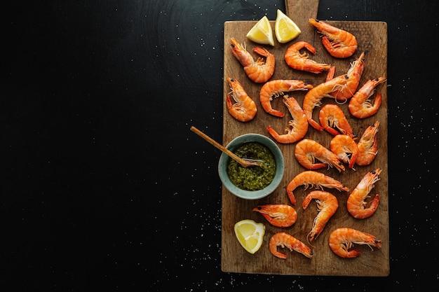 Lekkere garnalen met kruiden en saus aan boord op een donkere ondergrond