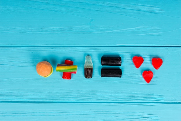 Lekkere gelei-snoepjes vertegenwoordigen in de vorm van een hamburger en een drankje dat liefde is op een houten turquoise tafel