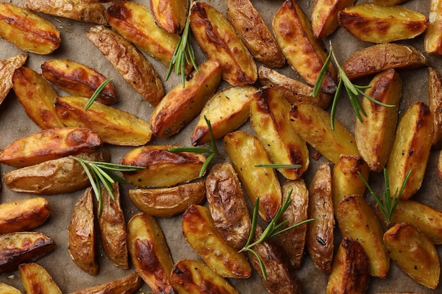 Foto lekkere gepofte aardappel en aromatische rozemarijn op perkamentpapier plat gelegd