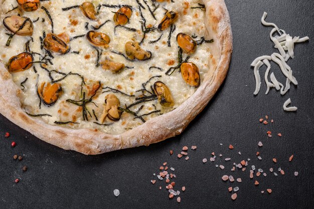 Lekkere gesneden pizza met zeevruchten en tomaat op zwarte achtergrond. Mediterrane keuken