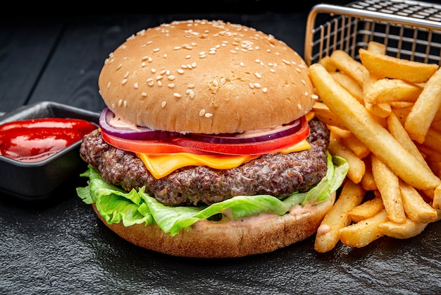 Lekkere hamburger en frietjes op een zwarte houten tafel