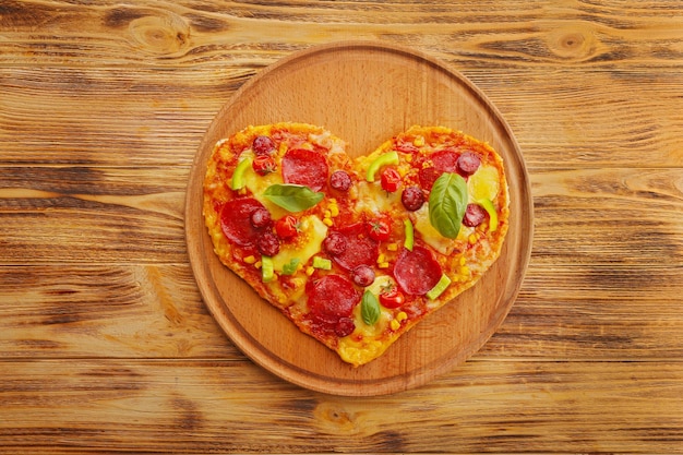 Lekkere hartvormige pizza op houten achtergrond