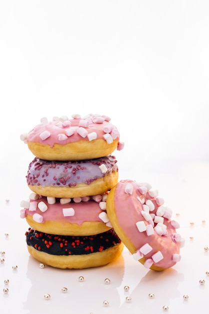 Lekkere heerlijke zoete noten met kleurrijke hagelslag op een witte achtergrond die is ontsproten aan vijf zoete donuts