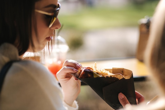 Lekkere hotdog in handen van vrouwen, meisjes kopen straatvoedsel dagelijkse routines tijdens de lunchpauze