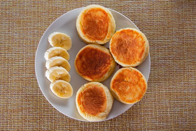 Lekkere kaas pannenkoeken met jam op een bord op een bruine achtergrond. Ontbijt