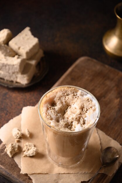 Lekkere koffie latte met halva in glazen beker.