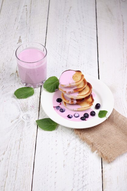 Lekkere mooie pannenkoeken met bosbessen en bosbessenyoghurt op een lichte houten tafel met muntblaadjes.