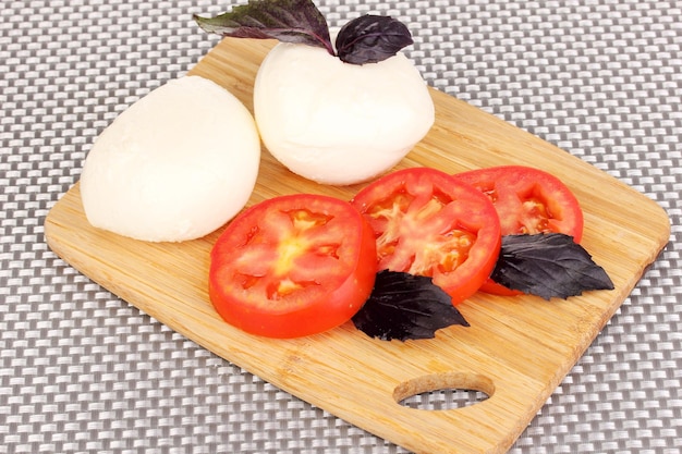 Lekkere mozzarella met tomaten op snijplank op mat