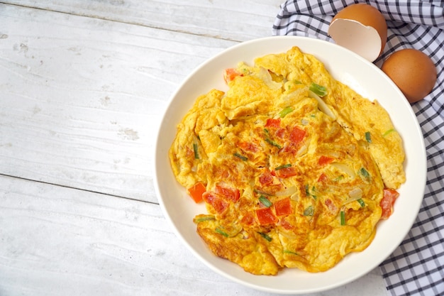 Lekkere Omelet (Omeltette) met tomaat, groene ui op witte plaat. Vers ingrediënt.