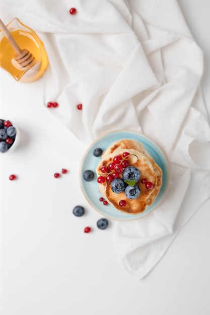 Lekkere pannenkoeken met verse bosbessenframbozen en honing, gezond ochtendontbijt in rustieke stijl