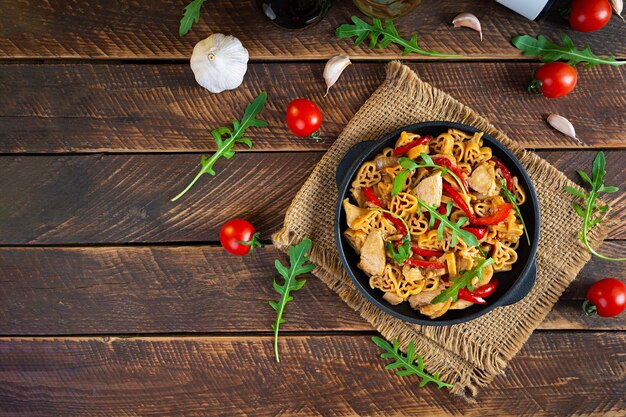 Lekkere pasta in tomatensaus met kip, peper en kruiden op houten achtergrond. Bovenaanzicht