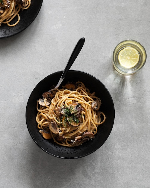 Lekkere pasta met champignons geserveerd op bord met groene kaas en kruiden op een donkere achtergrond