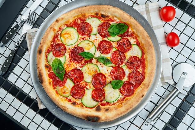 Lekkere pizza met salami, courgette en basilicum op een witte tafel. Italiaanse traditionele keuken. Heerlijk eten plat liggen. Bovenaanzicht