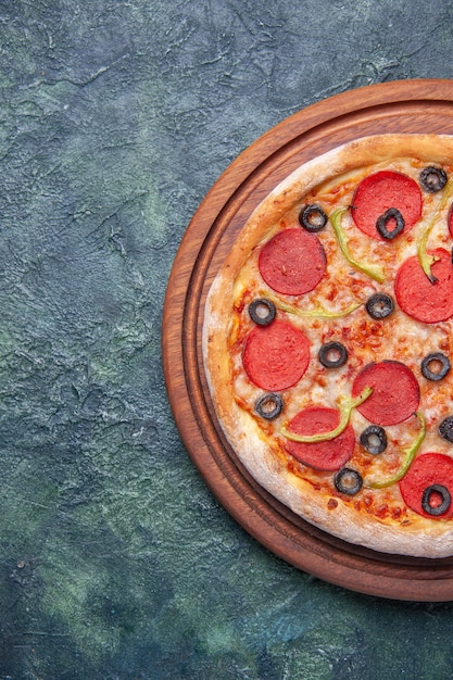 Lekkere pizza op houten snijplank aan de linkerkant op geïsoleerde donkere ondergrond met vrije ruimte