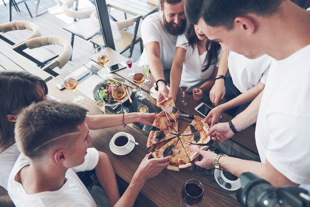 Lekkere pizza op tafel, met een groep jonge lachende mensen rusten in de pub