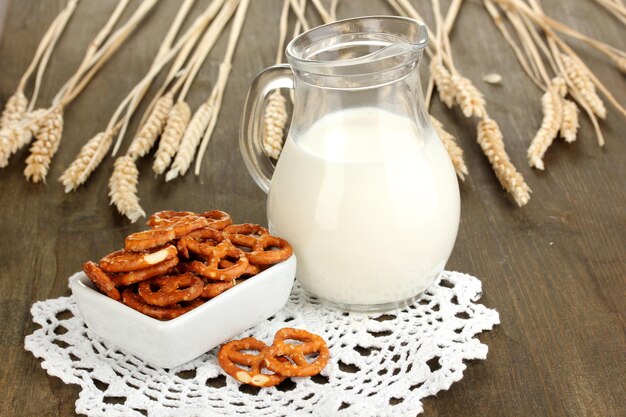 Lekkere pretzels in witte kom en melkkan op houten tafel close-up