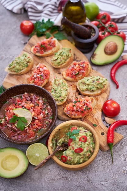 Lekkere salsa en guacamole bruschetta-snacks in de binnenlandse keuken op houten snijplank