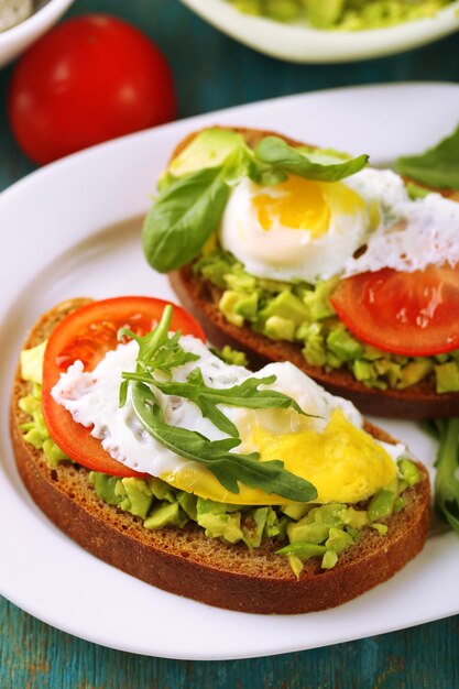 Lekkere sandwiches met ei, avocado en groenten op plaat op houten achtergrond