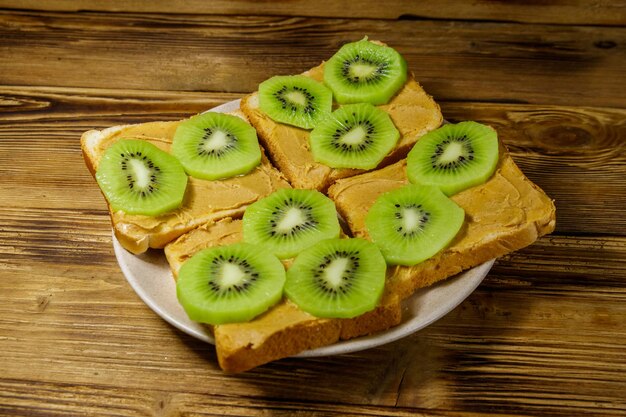 Lekkere sandwiches met pindakaas en kiwi's op houten tafel