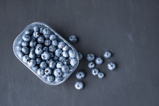 Lekkere sappige rauwe bosbessen in een plastic container op een zwarte donkere