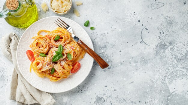 Lekkere smakelijke klassieke italiaanse tagliatelle pasta met tomatensaus, kaas Parmezaanse kaas en basilicum op plaat op lichttafel. Bekijk van bovenaf, horizontaal. Bovenaanzicht met kopie ruimte.