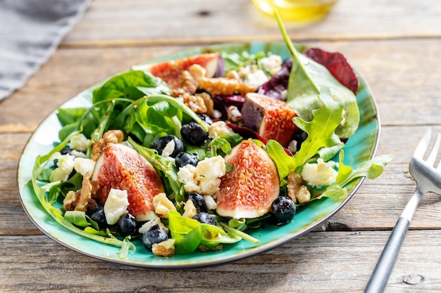 Lekkere smakelijke salade met rucola vijgen kaas en noten geserveerd op tafel. Detailopname