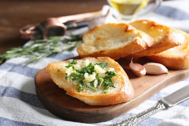 Lekkere sneetjes brood met knoflook en kruiden op houten snijplank