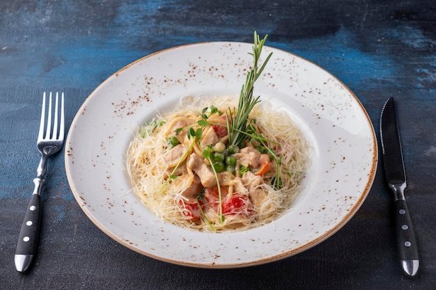 Lekkere spaghetti met kip groenten en kaas geserveerd met mes en vork