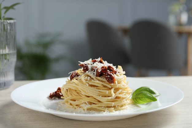 Lekkere spaghetti met zongedroogde tomaten en Parmezaanse kaas op houten tafel in restaurant close-up Prachtige presentatie van pastaschotel