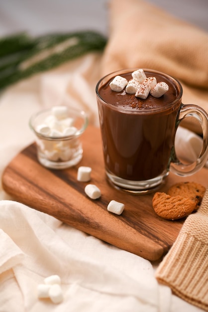 Lekkere warme chocolademelk met marshmallow en koekjes op een houten dienblad in een gezellige minimale tafel