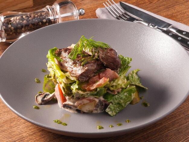 Lekkere warme salade met kalfsvlees, groenten en champignons in het restaurant