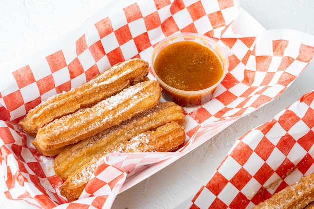 Lekkere warme zoete churros in papier met chocolade en karamel in een papierlade