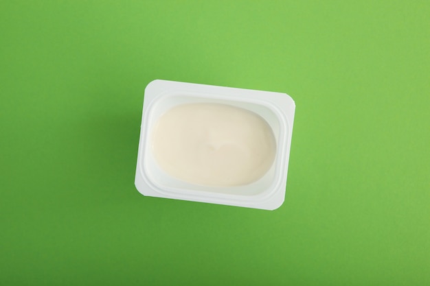 Lekkere yoghurt in een plastic glas op een gekleurde tafel om tekst in te voegen