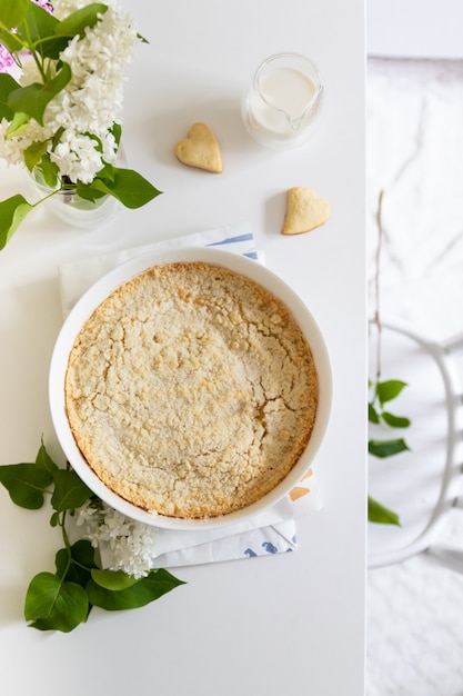 Lekkere zelfgemaakte cheesecake in witte schotel op een tafel met seringen