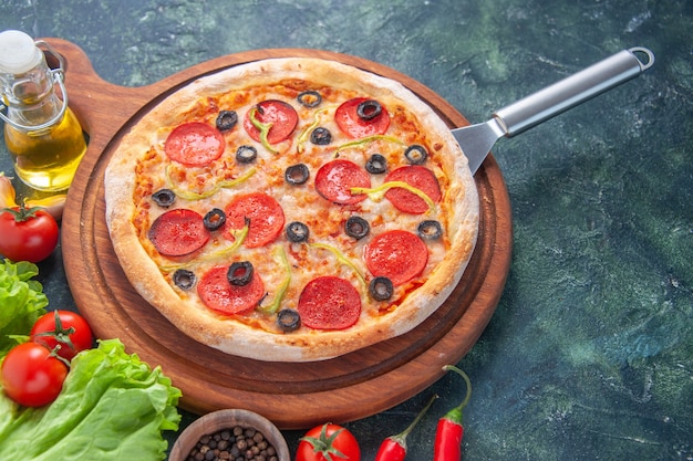 Lekkere zelfgemaakte pizza op houten bord oliefles tomaten peper groene bundel op donkere ondergrond