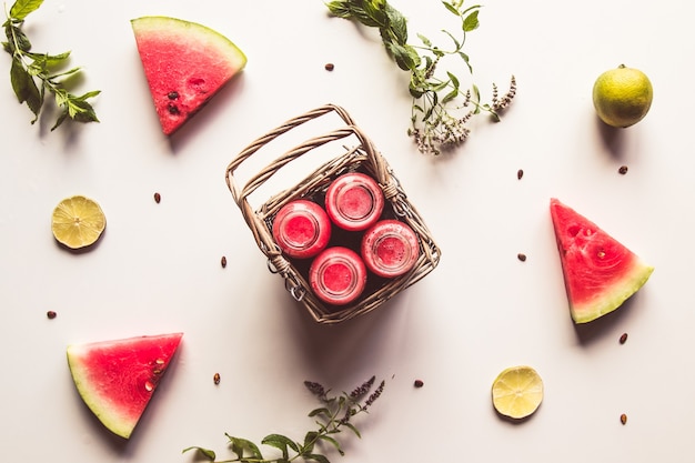 Lekkere zomer gebotteld watermeloen drankje in een mand en plakjes vers fruit