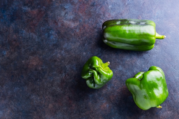 Lelijke paprika op donkere achtergrond. misvormde groene paprika van eigen bodem. kopieer ruimte. bovenaanzicht