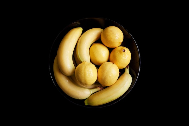 Lemon and banana on a black plate