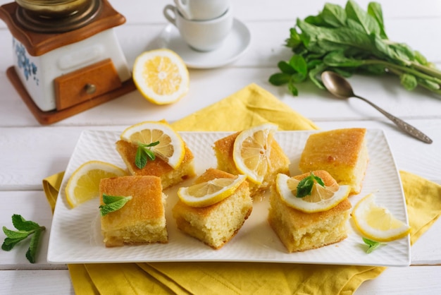 Foto biscotto al limone a fette quadrate guarnito con fettine di limone fresco e foglie di menta combinazione di colori giallo