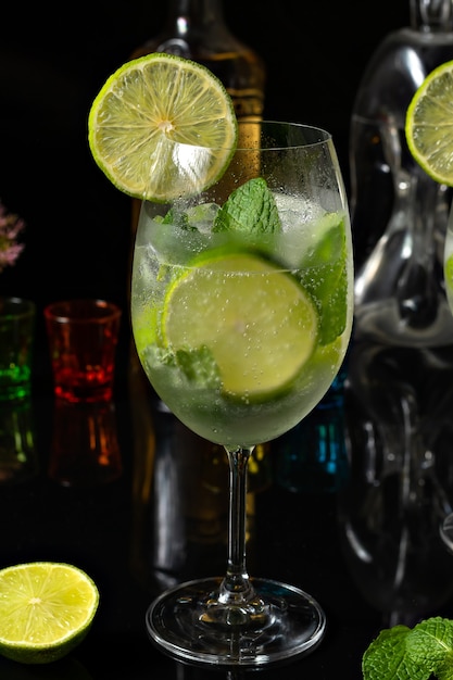 lemon cocktail in a glass goblet on a reflective black background gin and tonic drink with lemon