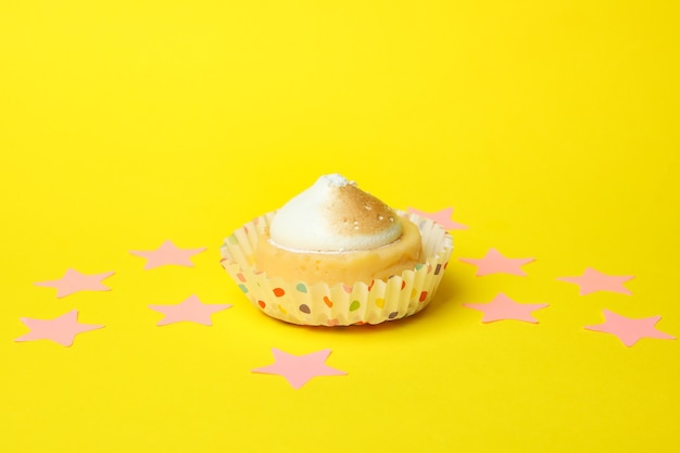 Lemon cupcake and pink stars on yellow background