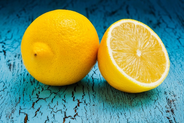 Lemon and cut half slice on blue wooden background