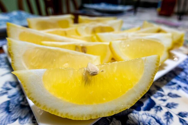 Lemon cut into wedges and presented on a serving plate focus is on the foreground specimen