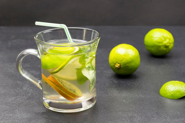 Lemon drink with green basil in a glass Limes on the table